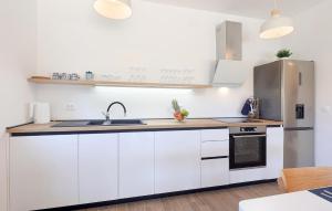 a kitchen with white cabinets and a stainless steel refrigerator at Lovely Home In Pasman in Pašman