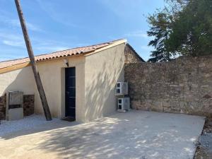 a building with a door next to a wall at Maison en Pierre à Clermont-l'Hérault in Brignac