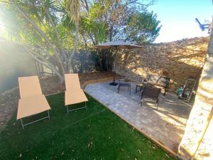a patio with tables and chairs and an umbrella at Maison en Pierre à Clermont-l'Hérault in Brignac +1 photo