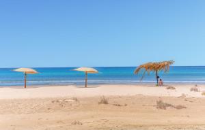 drei Strohschirme an einem Strand mit Blick auf das Meer in der Unterkunft Amazing Apartment In Marina Di Modica in Marina di Modica