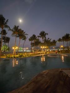 a large swimming pool with palm trees and a moon at Casa Naluum B02 in Passo de Camarajibe