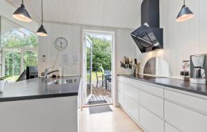 a kitchen with white cabinets and a clock on the wall at Awesome Home In Glesborg With Sauna in Glesborg