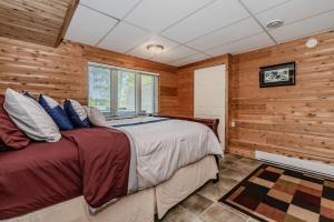 una camera da letto con un letto in una stanza con pareti in legno di Lakeside Retreat With Hot Tub & Dock a Lion's Head