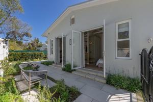 a white house with a patio and a fence at The Olive Cottage in Constantia in Cape Town