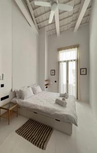 a white bedroom with a bed and a ceiling fan at The Bridge House Plomari in Plomari +34 photos