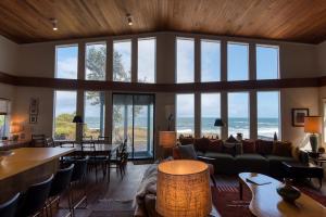 a living room with a couch and tables and windows at #StayinMyDistrict Cape Arago Sanctuary at the Sea in Coos Bay