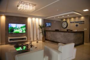 a lobby with a waiting room with a tv on the wall at Hotel Imperatriz Premium in Telêmaco Borba