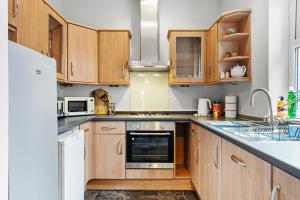 a kitchen with wooden cabinets and a white refrigerator at Stylish 6-BR home, Monthly Savings, Free Parking in Nether Edge