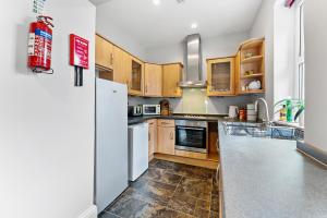 une cuisine avec des armoires en bois et un réfrigérateur blanc dans l'établissement Elegant 6-BR home, Monthly Savings, Free Parking, à Nether Edge