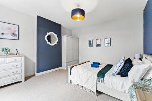 - une chambre avec un lit et un mur bleu dans l'établissement Elegant 6-BR home, Monthly Savings, Free Parking, à Nether Edge