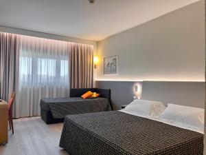 a hotel room with two beds and a window at The Sydney Hotel in Bologna