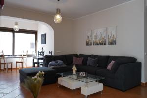 波尔蒂芒Sky and Sand Hostel的客厅里有一张黑色沙发和一张桌子