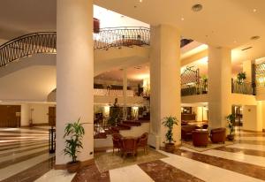 una grande hall con scale, sedie e tavoli di Grand Hotel Barone Di Sassj a Sesto San Giovanni