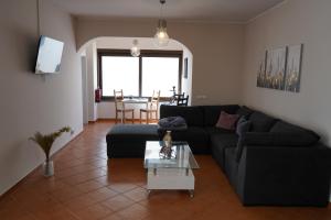 a living room with a black couch and a table at Sky and Sand Hostel in Portimão