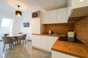 une cuisine avec des armoires blanches et une table avec des chaises dans l'établissement BelVie Residence, à Vienne