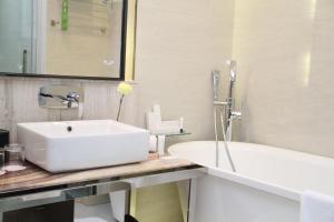 a bathroom with a white sink and a tub at Fleuve Congo Hotel By Blazon Hotels in Kinshasa