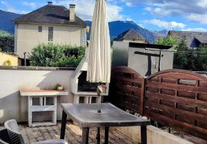 un patio con sombrilla y una mesa en un balcón en Charmant T2 au pied des Pyrénées - Argeles Gazost, en Argelès-Gazost