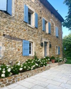 a stone house with blue shuttered windows and flowers at Domaine de la Lisière in Sault-de-Vaucluse