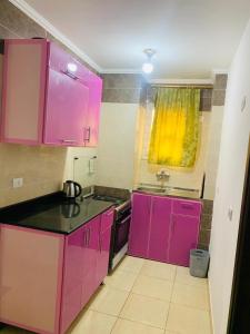 a kitchen with pink cabinets and a sink at مارينا دلتا in Al Ḩammād