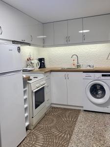a kitchen with white cabinets and a washing machine at Πέτρινο σπίτι δίπλα στη θάλασσα in Votsalákia