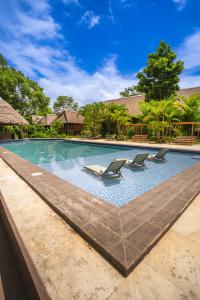 a swimming pool with lounge chairs in a resort at IKAM Riverview Amazon Lodge - Asociado Casa Andina in Puerto Maldonado