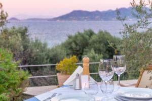 a table with wine glasses and a view of the water at Armonia Bay Hotel in Kokkari