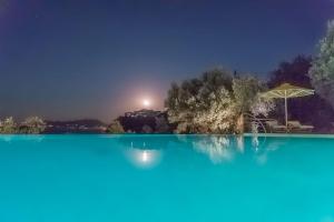 a swimming pool at night with an umbrella at Armonia Bay Hotel in Kokkari