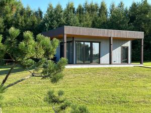a house in a field with a tree at Five Pine Resort in Darbėnai