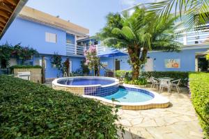 a swimming pool in front of a blue building at Velinn Pousada Remanso do Mar in Ubatuba