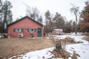 a red house with a green door in a yard at Black bear cabin with blow up hot tub in Necedah