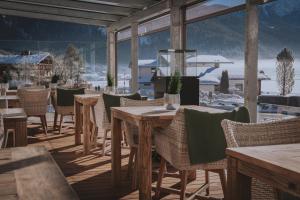 a restaurant with tables and chairs with a view of snow covered mountains at loisi's Boutiquehotel in Achenkirch
