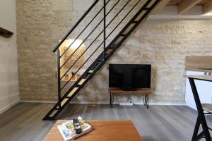 a living room with a tv and a staircase at Le duplex du 71 B in Niort