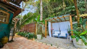 a patio of a house with a bench and trees at Manacá Suítes Prumirim in Ubatuba