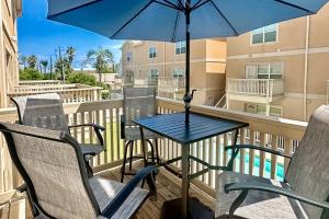 a balcony with a table and chairs and an umbrella at Star Beachside Condominiums 106 in South Padre Island