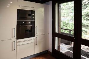 a kitchen with white cabinets and a microwave and a window at Résidence Chal. Les Chandelles - CHALET Les Chandelles 11 Pers. PIED PISTES MAE-6521 in Les Orres