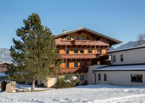 un grande edificio con un albero nella neve di Landhaus Greil a Reith im Alpbachtal