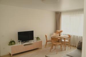 a living room with a television and a table with chairs at Haustory Apartment in Klaipėda +13 photos