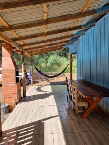 a porch with a hammock and a wooden table and bench at Rancho do Pijuca - Usina Mauá in Ortigueira