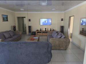 a living room with two couches and a flat screen tv at SammyGrace Holiday Home in Tzaneen