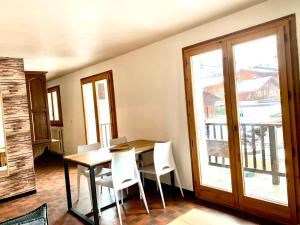a dining room with a table and white chairs at La clusaz Centre village , pied des pistes, 42 m2 , balcon sud vue montagne in La Clusaz