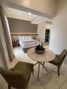 a bedroom with a bed and a table and chairs at Hotel Capital Das Pedras in Teófilo Otoni