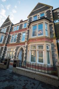 una gran casa de ladrillo con una valla negra en Aaron Wise Apartments, en Cardiff