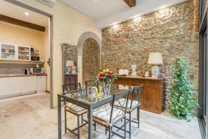 een eetkamer met een tafel en stoelen en een stenen muur bij Little Patio in Florence