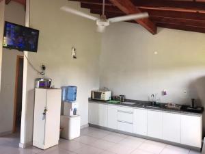 a kitchen with a refrigerator and a tv on the wall at Casa Quinta Sagrada Familia de Nazaret in Guarambaré