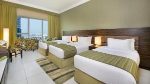a hotel room with two beds and a balcony at Atana Hotel in Dubai