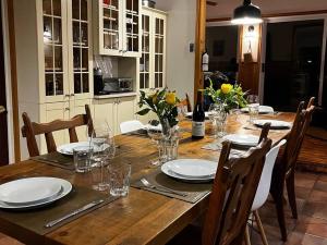 a wooden table with chairs and plates and wine glasses at Du Bonheur Lac Pare - Waterfront, Spa & FirePit in Grande Vallee +40 photos