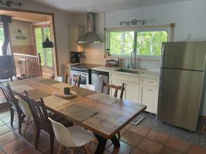 a kitchen with a wooden table and a refrigerator at Du Bonheur Lac Pare - Waterfront, Spa & FirePit in Grande Vallee