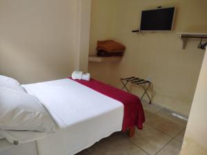 a bedroom with a white bed with a red blanket at Caminito in Santo Antônio do Pinhal