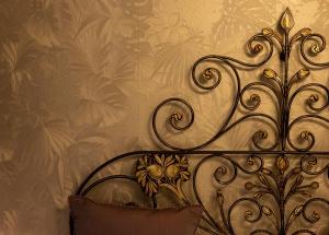 a metal bed frame with flowers on a wall at Fiordiloto B&B 4 STARS in Alba