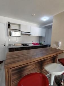 a kitchen with a large wooden counter with a red chair at Apartamento de estreno in Arequipa